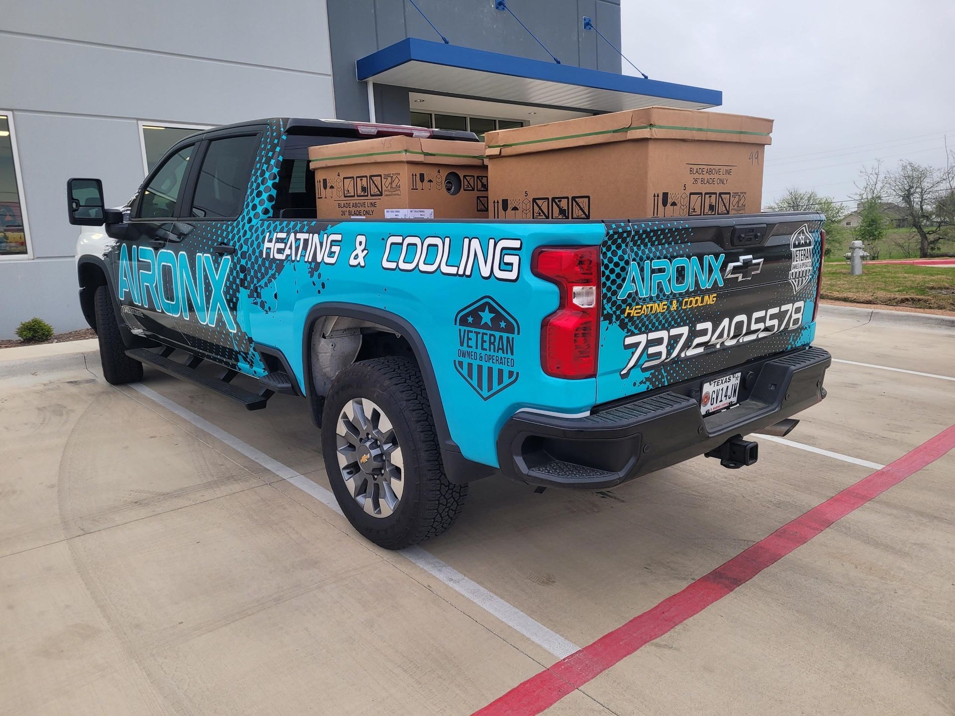 Blue truck with Aironx Heating & Cooling branding parked, carrying large boxes in the bed.