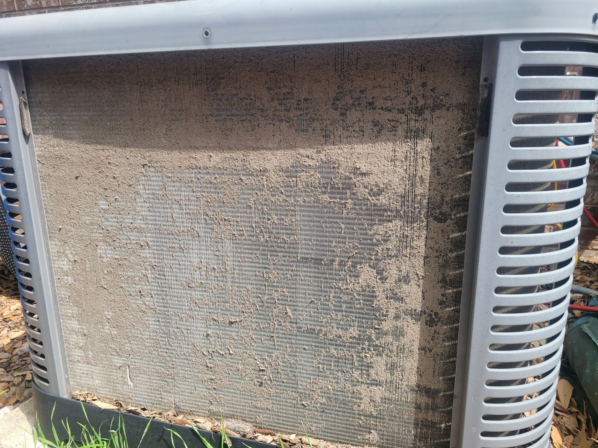 Close-up of a dirty outdoor air conditioning unit with accumulated dust on the coils.